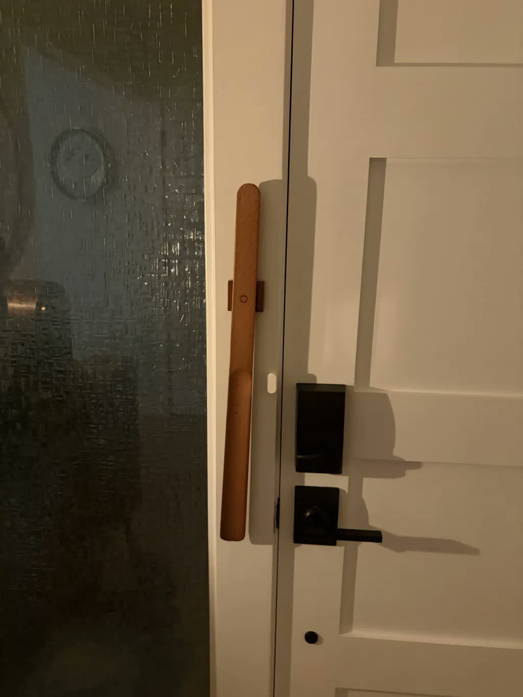 Ljust bokskohorn magnetiskt monterat på vit dörrkarm bredvid svart dörrhandtag och smartlås