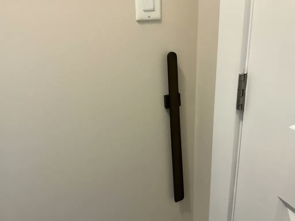 Nästan svart skohorn på beige vägg bredvid en vit dörr, med strömbrytare ovanför