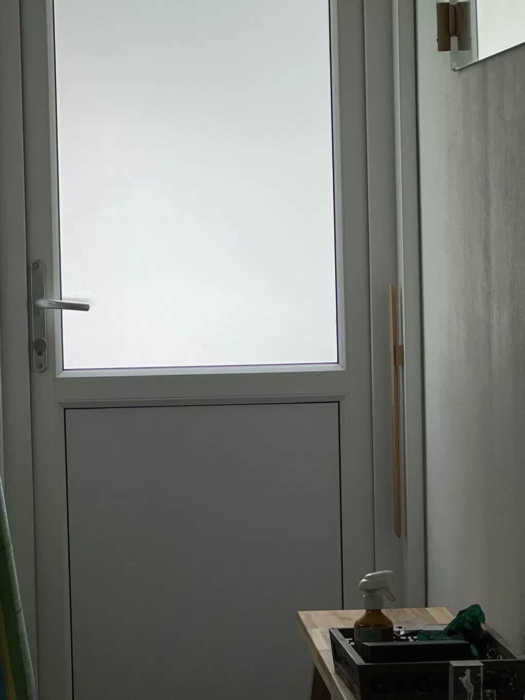 Skohorn i naturlig bok på gråbeige vägg bredvid vit trädgårdsdörr med frostat glas