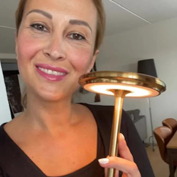 Kund håller upp Copenhagen bordslampa i guld framför sig